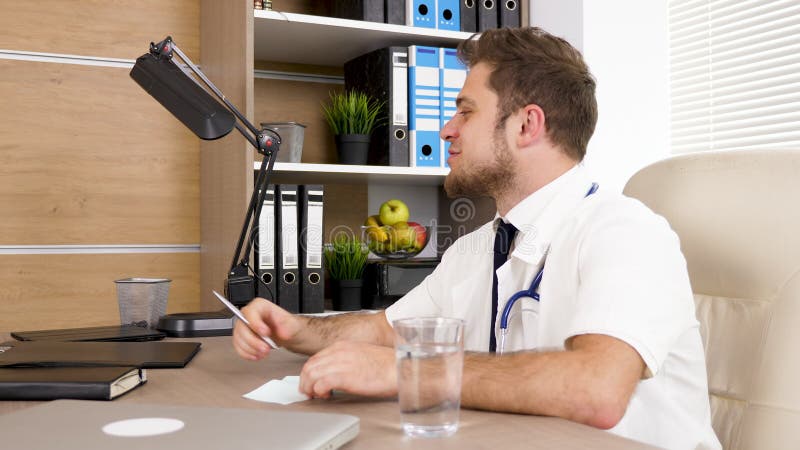 Doktor am Schreibtisch im Büro sprechend mit seinem Kollegen und Lächeln stock footage