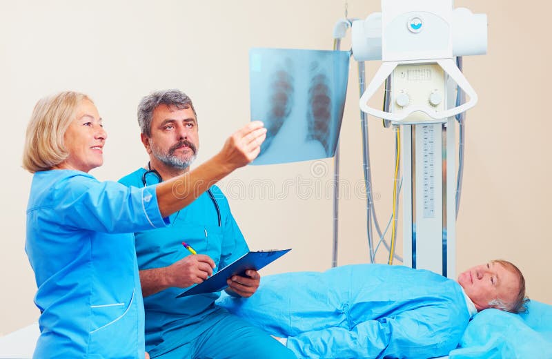 Doktoren, die das Röntgenfunktelegramm im Röntgenstrahlraum mit Patienten besprechen lizenzfreie stockbilder Doktoren, die das Röntgenfunktelegramm im Röntgenstrahlraum mit Patienten besprechen lizenzfreie stockbilder