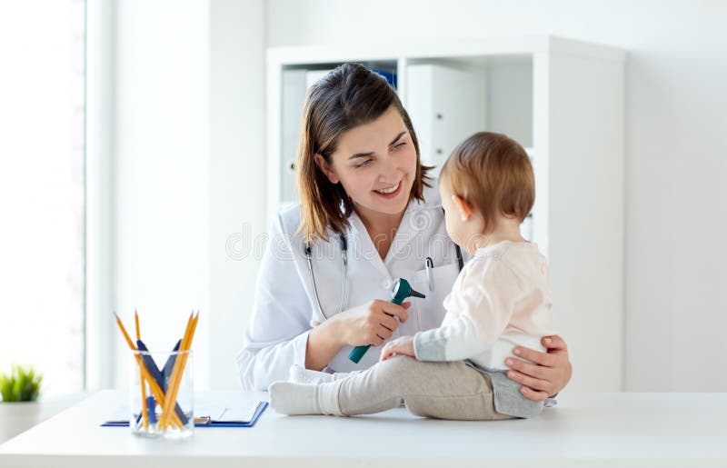 Doktorn med behandla som ett barn och otoscopen på kliniken royaltyfri bild Doktorn med behandla som ett barn och otoscopen på kliniken royaltyfri bild