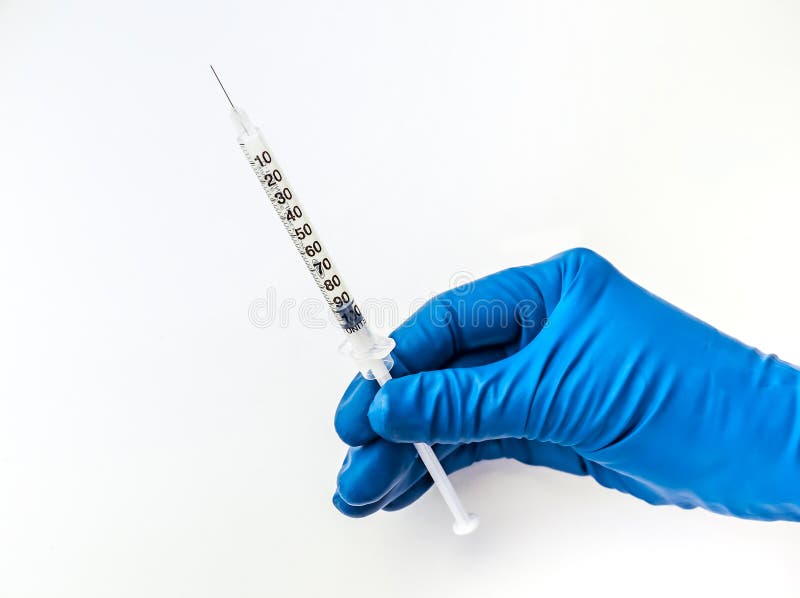 Doktors hand i den blåa medicinska handsken som rymmer den öppna injektionssprutan med medicinsk lösning isolerad vit bakgrund In arkivfoton Doktors hand i den blåa medicinska handsken som rymmer den öppna injektionssprutan med medicinsk lösning isolerad vit bakgrund In arkivfoton