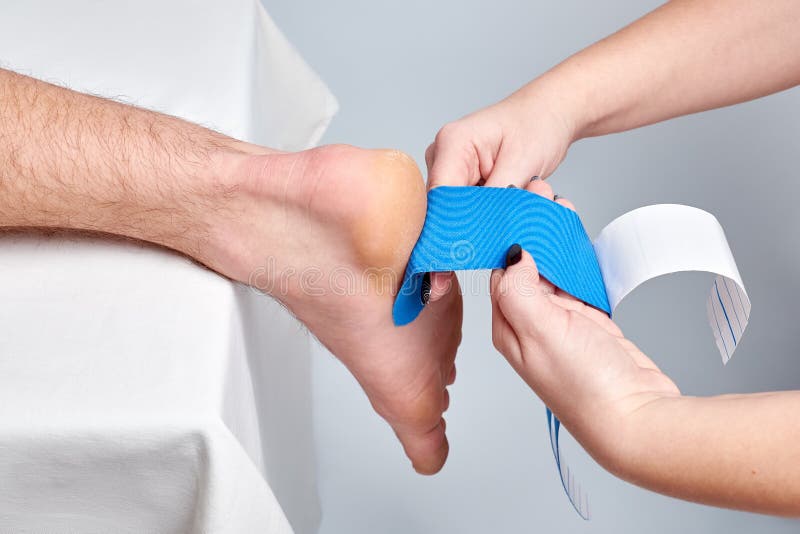 Doktorsfysioterapeuthänder som applicerar medicinskt tejpa för kinesio på ankeln royaltyfria foton Doktorsfysioterapeuthänder som applicerar medicinskt tejpa för kinesio på ankeln royaltyfria foton