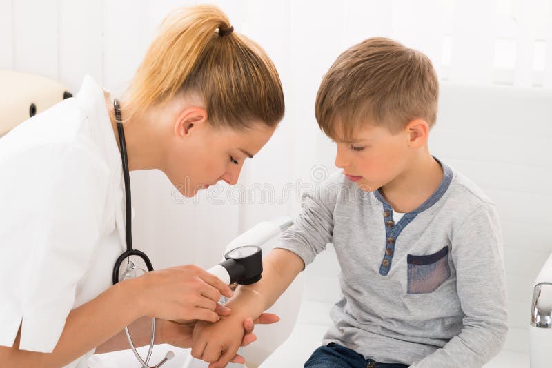 Female Doctor Examining Skin Of Little Boy With Dermatoscope. Female Doctor Examining Skin Of Little Boy With Dermatoscope