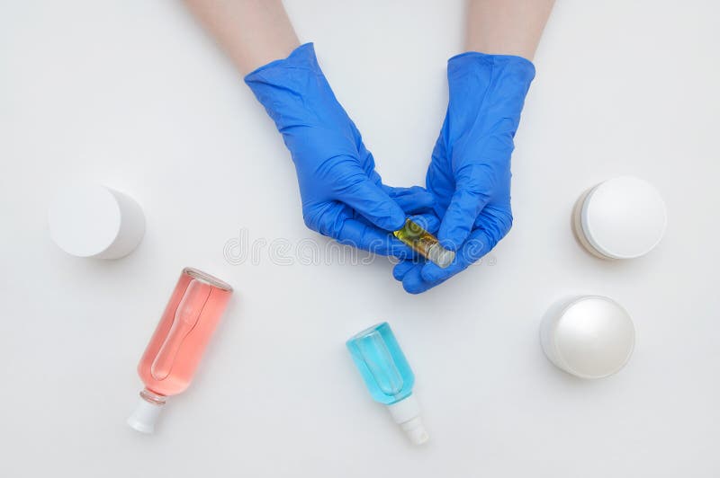 Doktorski beautician w błękitnych rękawiczkach trzyma ampułkę w rękach za obrazy royalty free Doktorski beautician w błękitnych rękawiczkach trzyma ampułkę w rękach za obrazy royalty free