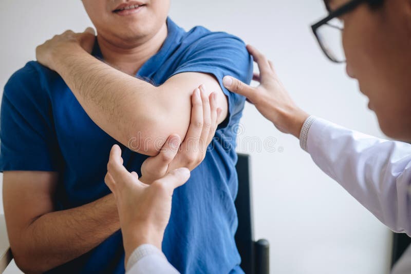 Doktorski physiotherapist pomaga męskiego pacjenta podczas gdy dawać ćwiczący traktowanie masuje rękę pacjent w physio pokoju, zdjęcie royalty free Doktorski physiotherapist pomaga męskiego pacjenta podczas gdy dawać ćwiczący traktowanie masuje rękę pacjent w physio pokoju, zdjęcie royalty free