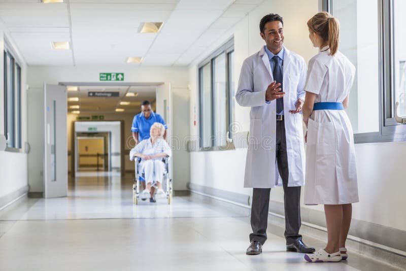 Doktorski & pielęgniarka Starszy Żeński Cierpliwy wózka inwalidzkiego szpital Corrido obraz stock Doktorski & pielęgniarka Starszy Żeński Cierpliwy wózka inwalidzkiego szpital Corrido obraz stock