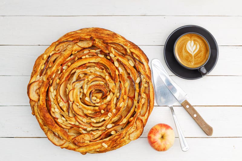 Dolce e pasticcini di cannella, di mele e di cannella, freschi, cotti in forno, fritti e tazza di caffè su tavolo di legno bianco immagini stock Dolce e pasticcini di cannella, di mele e di cannella, freschi, cotti in forno, fritti e tazza di caffè su tavolo di legno bianco immagini stock