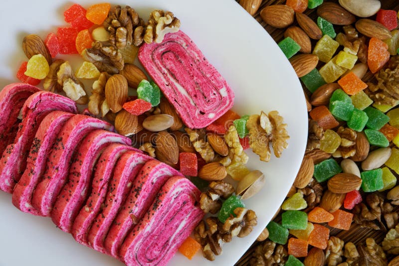 Dolci arabi: halvah rosa insolito in un piatto bianco accanto ai frutti canditi, ai pistacchi, alle mandorle ed alle noci Orienta fotografia stock Dolci arabi: halvah rosa insolito in un piatto bianco accanto ai frutti canditi, ai pistacchi, alle mandorle ed alle noci Orienta fotografia stock