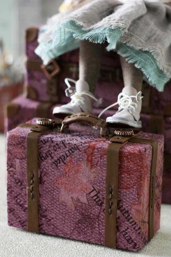 The doll sits on a miniature doll suitcase royalty free stock photo