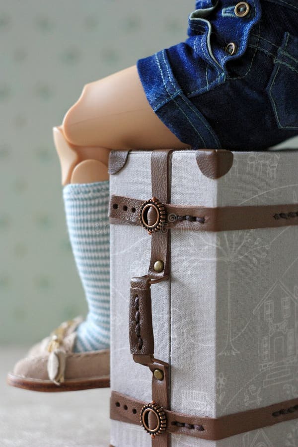 The doll sits on a miniature doll suitcase stock photos