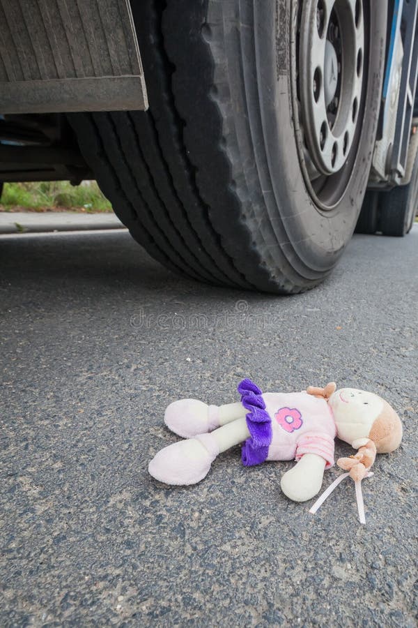 Wheels of a truck and a doll on the asphalt after an accident with a little child. Wheels of a truck and a doll on the asphalt after an accident with a little child