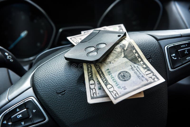 100 Dollarscheine mit Autoschlüssel innerhalb des Autos. Bestechung- oder Kaufmietkonzept lizenzfreie stockfotografie