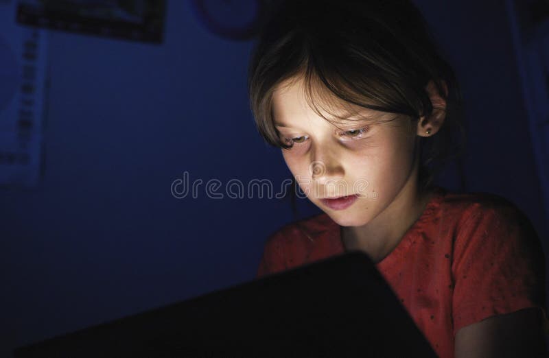 Dolly geschoten Kaukasisch meisje in bed het spelen tablet in Internet in donkerblauw licht onder blacket stock fotografie Dolly geschoten Kaukasisch meisje in bed het spelen tablet in Internet in donkerblauw licht onder blacket stock fotografie