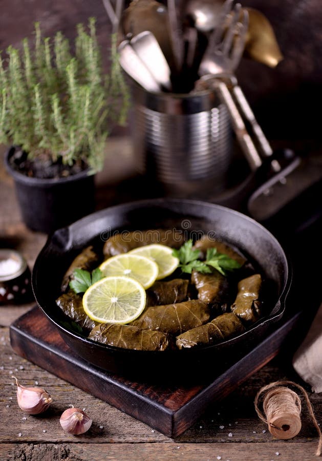 Dolma, folhas de uva enchida com arroz e carne triturou a carne em uma frigideira do ferro fundido em um fundo de madeira velho C fotografia de stock Dolma, folhas de uva enchida com arroz e carne triturou a carne em uma frigideira do ferro fundido em um fundo de madeira velho C fotografia de stock
