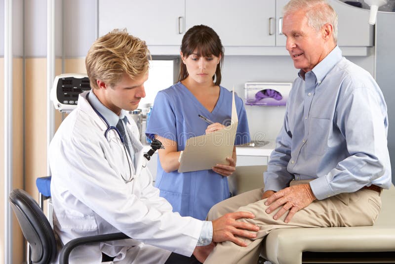 Dolor de la rodilla del doctor Examining Male Patient With