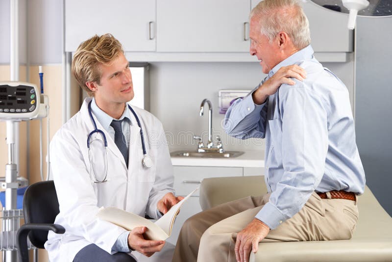 Dolor del hombro del doctor Examining Male Patient With