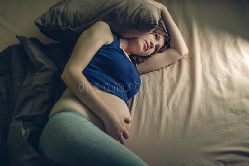Dolore di sensibilità della donna incinta in sua pancia che si trova a letto con l'insonnia alla notte Concetto della gravidanza immagini stock libere da diritti Dolore di sensibilità della donna incinta in sua pancia che si trova a letto con l'insonnia alla notte Concetto della gravidanza immagini stock libere da diritti