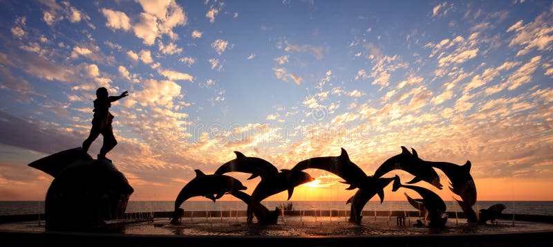 Dolphin statue in front of sunset stock images