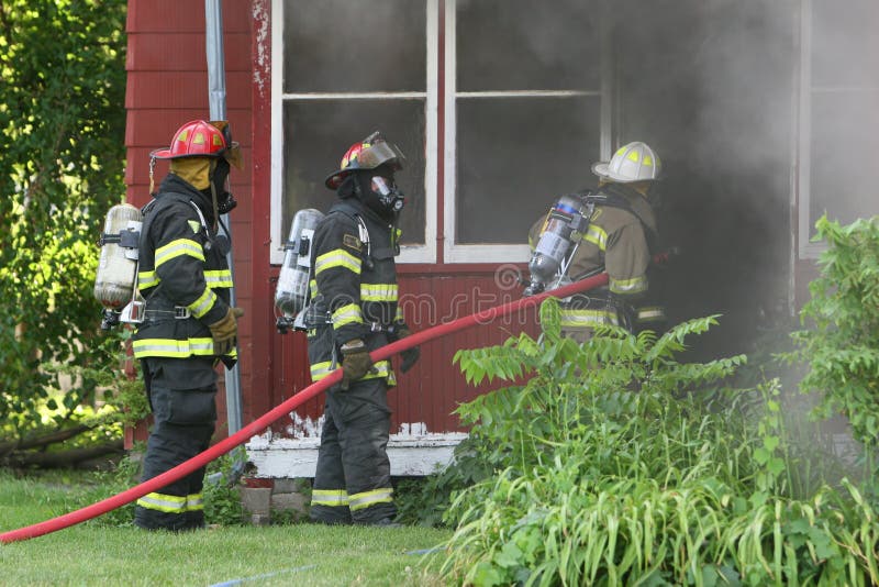 Three firemen work to out out a house fire in the midwest. Three firemen work to out out a house fire in the midwest.