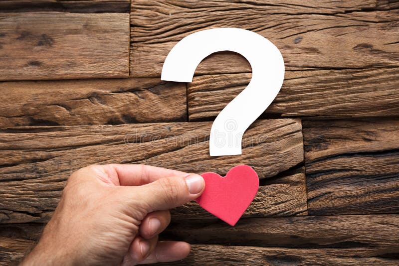 Domanda Mark With Heart On Wood della tenuta della mano fotografie stock Domanda Mark With Heart On Wood della tenuta della mano fotografie stock