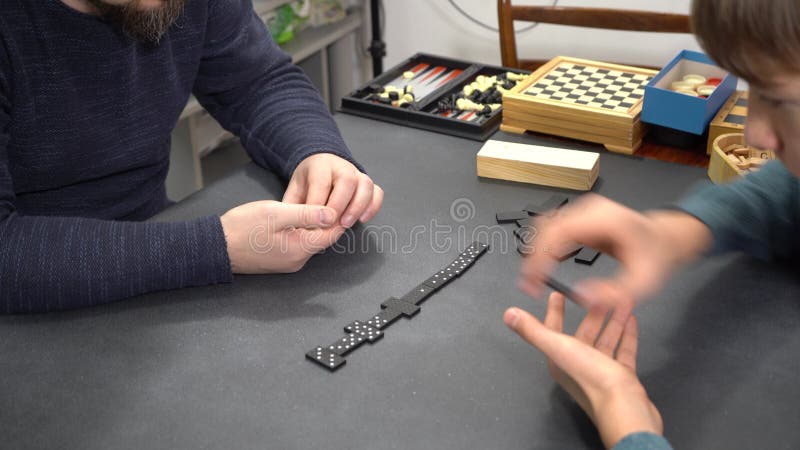 Domino de juego de mesa. Manos de los jugadores en la mesa. Tiempo de familia metrajes