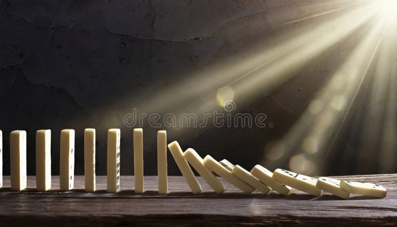 Dominoes topping in a line in dark environment copy space royalty free stock photo