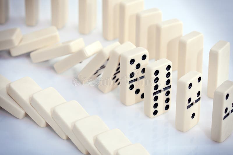 Stacked white dominoes falling over. Stacked white dominoes falling over.