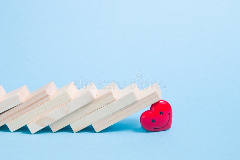 Dominosteine fielen auf einen Hintergrund-Kopienraum des Roten Herzens hellblauen stockfoto