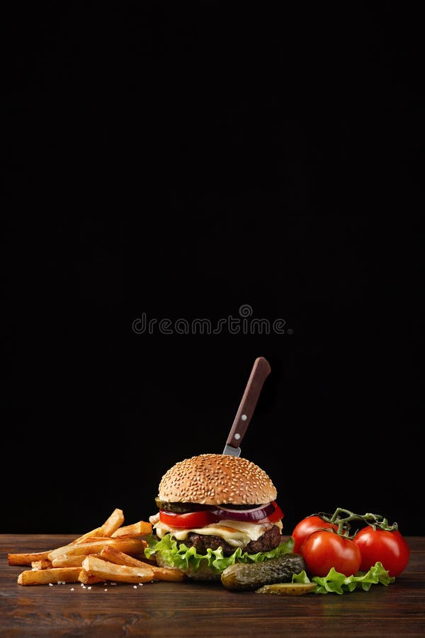 Domowej roboty hamburger w górę z wołowiny, pomidoru, sałaty, sera, cebuli i francuza dłoniaków na drewnianym stole, W hamburgerz zdjęcia stock Domowej roboty hamburger w górę z wołowiny, pomidoru, sałaty, sera, cebuli i francuza dłoniaków na drewnianym stole, W hamburgerz zdjęcia stock