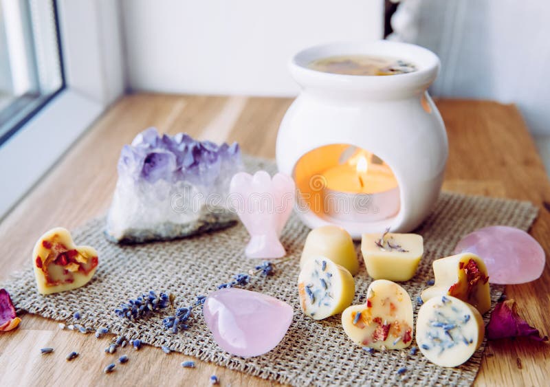 Homemade mini wax melts in aromatherapy lamp diffuser at home interior with rose quartz crystal hearts and angel for decoration on wooden window sill on winter. Seasonal spiritual zen concept. Homemade mini wax melts in aromatherapy lamp diffuser at home interior with rose quartz crystal hearts and angel for decoration on wooden window sill on winter. Seasonal spiritual zen concept.