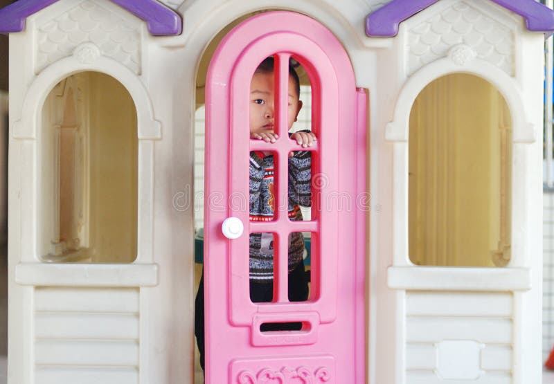 A Chinese boy play in a doll house, a plastic colorful doll house in a kindergarten. A Chinese boy play in a doll house, a plastic colorful doll house in a kindergarten.