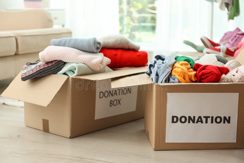 Donation Box with Clothes, Shoes and Soccer Ball on Table Stock Image