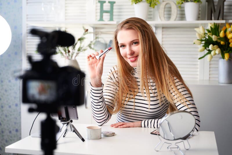 Donatorhona som visar läppstift. skönhetsbloggare som filmar daglig makeup-rutin i närheten av kamera på tripod arkivfoton