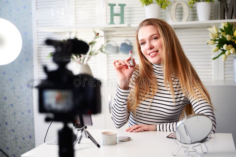 Donatorhona som visar läppstift. skönhetsbloggare som filmar daglig makeup-rutin i närheten av kamera på tripod royaltyfria bilder