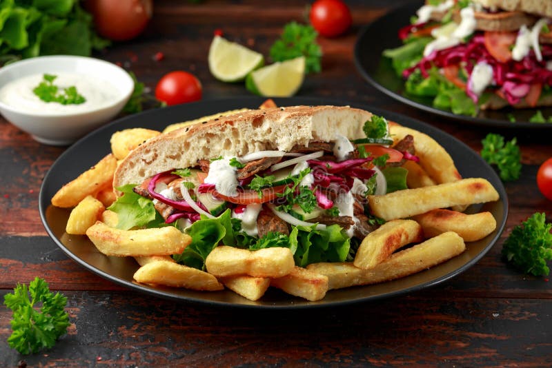 Doner kebab, fried lamb meat with vegetables, fries and garlic sauce in turkish bread