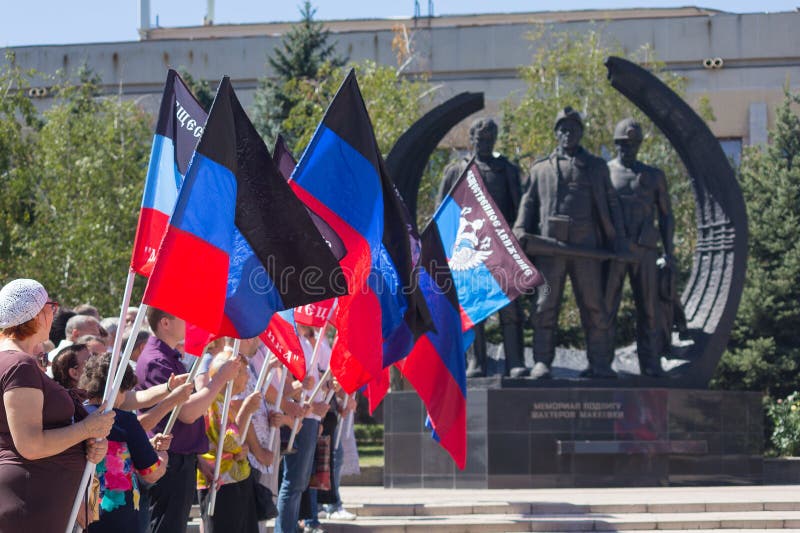 Donetsk, Ucrânia - 23 de agosto de 2018: Povos com as bandeiras da república do ` s dos povos de Donetsk que coloca flores no mem fotografia de stock Donetsk, Ucrânia - 23 de agosto de 2018: Povos com as bandeiras da república do ` s dos povos de Donetsk que coloca flores no mem fotografia de stock