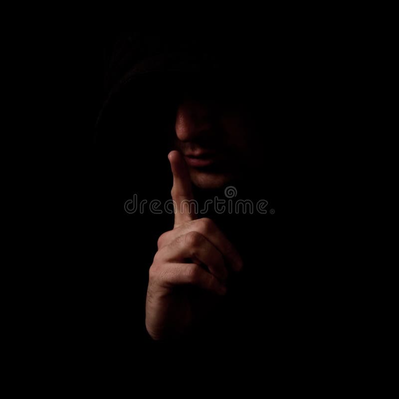 Man in the low light interior holding index finger over his mouth, making a Shh gesture. Man in the low light interior holding index finger over his mouth, making a Shh gesture.