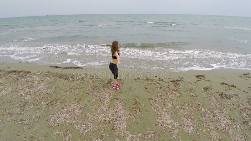 Donkerbruine vrouwelijke atleet opleiding op zandig strand, die hurkzit, sport en gezondheid doen