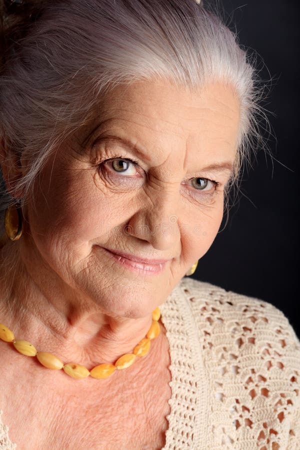 Portrait of a smiling senior woman. Studio shot over grey background. Portrait of a smiling senior woman. Studio shot over grey background.