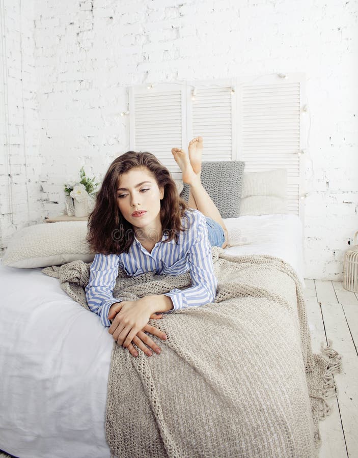 Young pretty brunette woman in her bedroom sitting at window, happy smiling lifestyle people concept close up. Young pretty brunette woman in her bedroom sitting at window, happy smiling lifestyle people concept close up