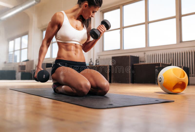 Donna adatta che risolve alla palestra con le teste di legno immagini stock Donna adatta che risolve alla palestra con le teste di legno immagini stock