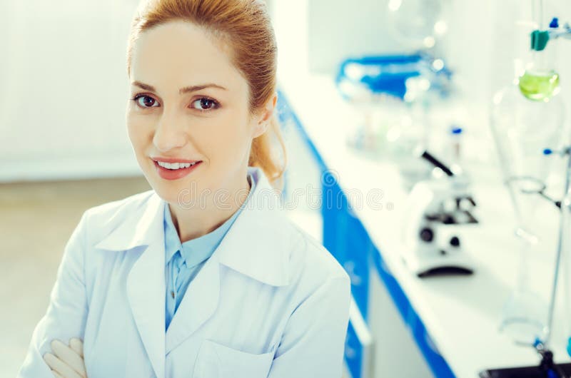 Donna adulta allegra che sorride mentre esaminando macchina fotografica in laboratorio fotografie stock libere da diritti Donna adulta allegra che sorride mentre esaminando macchina fotografica in laboratorio fotografie stock libere da diritti