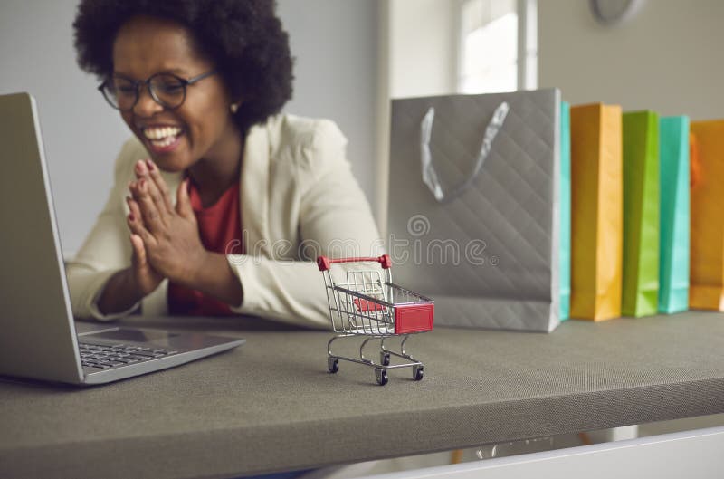Donna afro-americana felice che fa shopping online via laptop, si rallegra dell'offerta di vendita immagine stock libera da diritti