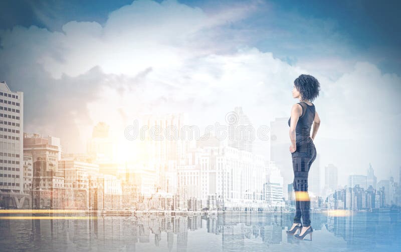 Donna afroamericana con le mani sulla vita, città immagine stock Donna afroamericana con le mani sulla vita, città immagine stock