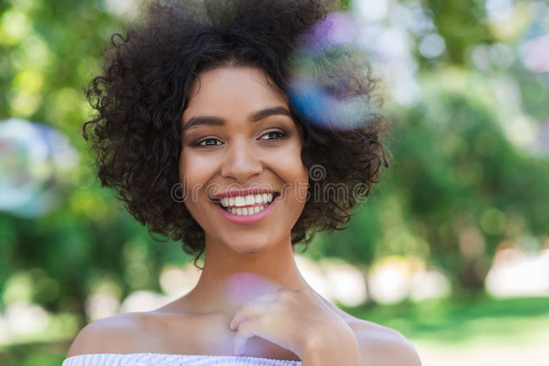 Donna afroamericana felice circondata dalle bolle in parco fotografia stock libera da diritti Donna afroamericana felice circondata dalle bolle in parco fotografia stock libera da diritti