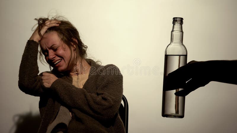 Donna alcolica che soffre forte ritiro, bottiglia maschio della tenuta della mano di vodka fotografia stock libera da diritti Donna alcolica che soffre forte ritiro, bottiglia maschio della tenuta della mano di vodka fotografia stock libera da diritti