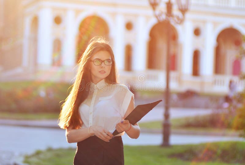 Donna alla moda di affari che tiene uno spazio in bianco di carta in sue mani e che posa sulla macchina fotografica il processo d immagine stock Donna alla moda di affari che tiene uno spazio in bianco di carta in sue mani e che posa sulla macchina fotografica il processo d immagine stock