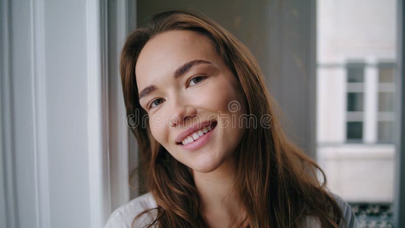 Donna allegra che sorride con una macchina fotografica nel ritratto di casa. ragazza positiva che gioca sui capelli fotografia stock