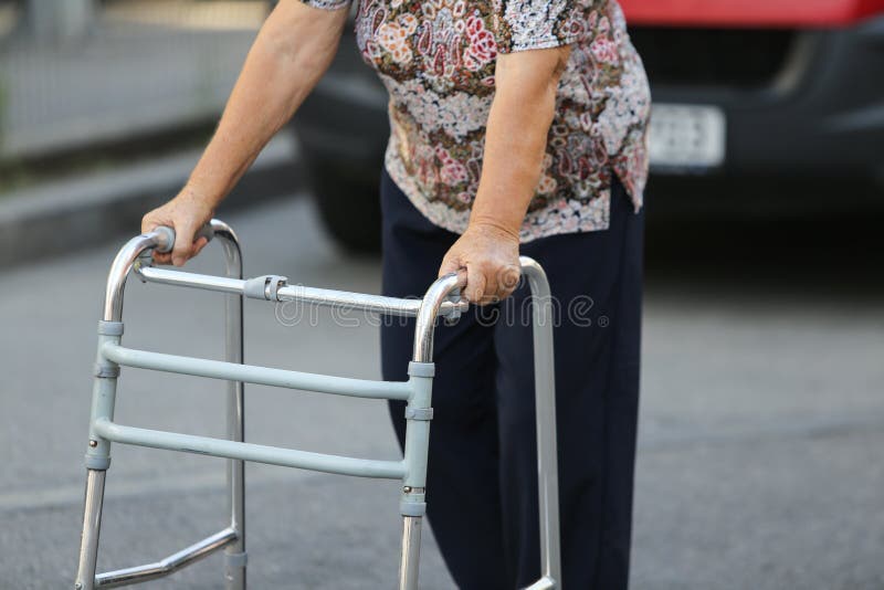 Donna anziana che usando un camminatore del metallo