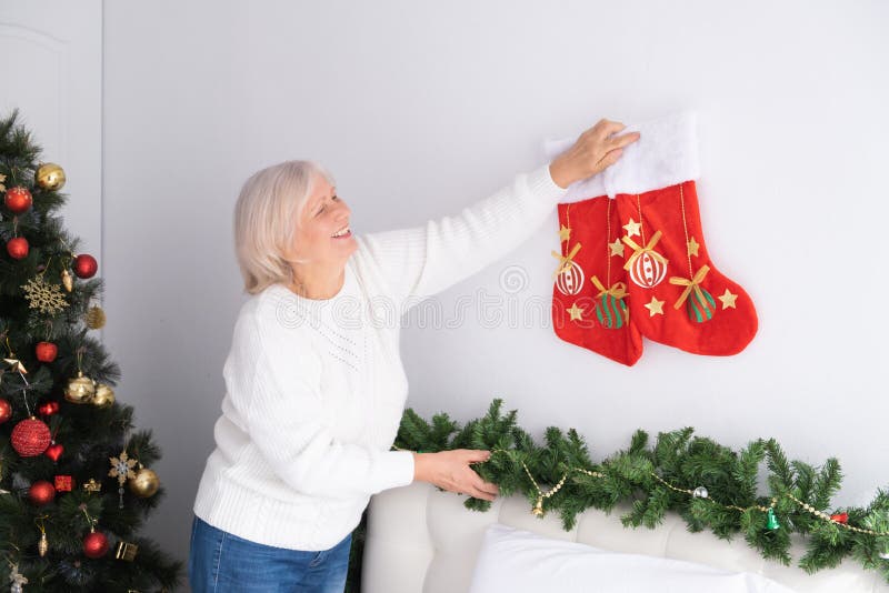Positive senior female decorating the room for Christmas. lifestyle indoor, old age and holidays concept. Positive senior female decorating the room for Christmas. lifestyle indoor, old age and holidays concept