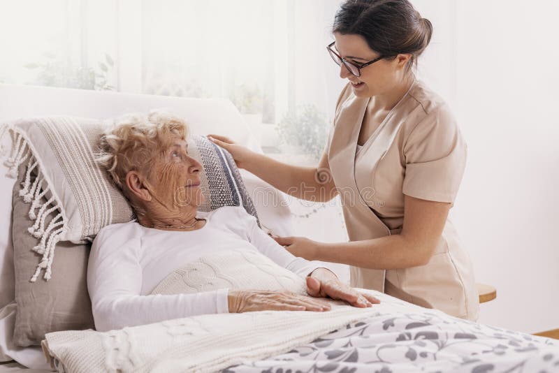 Elderly women in hospital bed with social worker helping her. Elderly women in hospital bed with social worker helping her